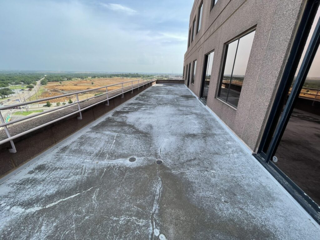 Skymark Tower high-rise balcony resurfacing project in Arlington, TX — tan silicone coating with broadcast granules