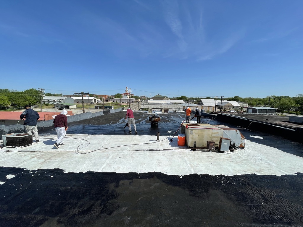 Failing bitumen flat roof well past its useful life before restoration at 170 N Center St, Bonham, TX