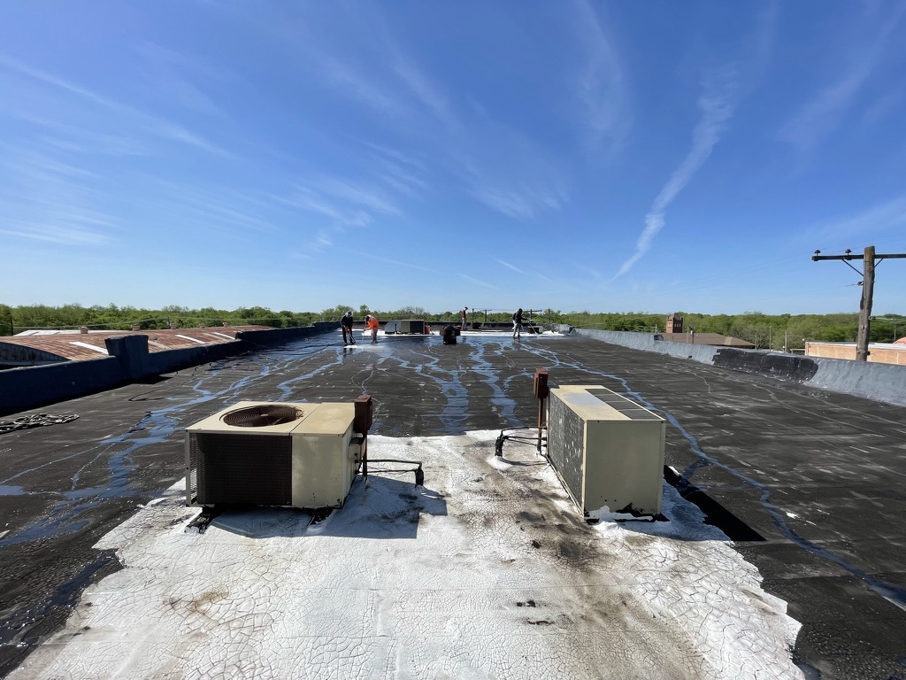 Silicone roof coating going down over the existing roofing system near the Bonham town square