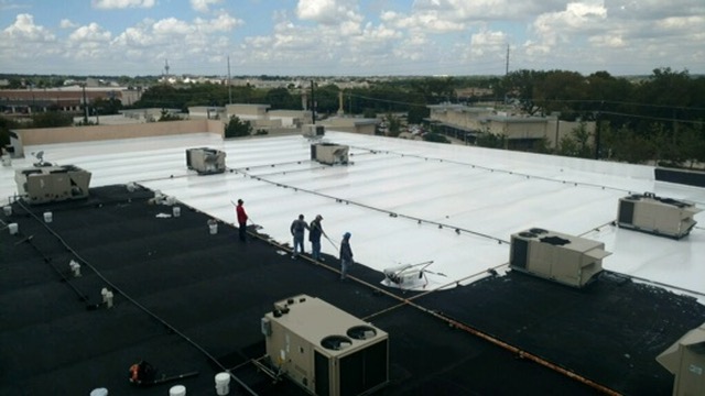 Overhead view of the Cedar Hill Crossing roof mid-project with white silicone coating over the completed section
