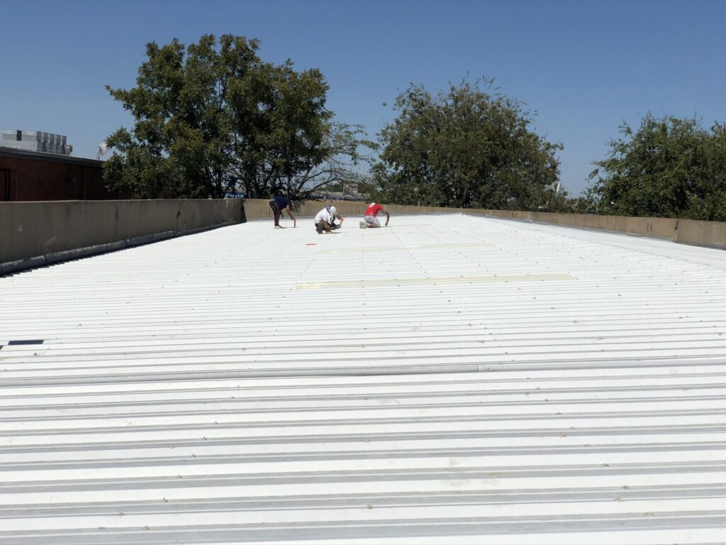 Silicone mastic sealing of fastener heads and roof seams on the industrial metal roof, Red Bird Industrial Park, Dallas