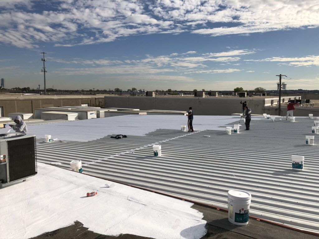 Silicone roof coating application over Modified Bitumen and R-panel sections at 3160 Irving Blvd, Dallas