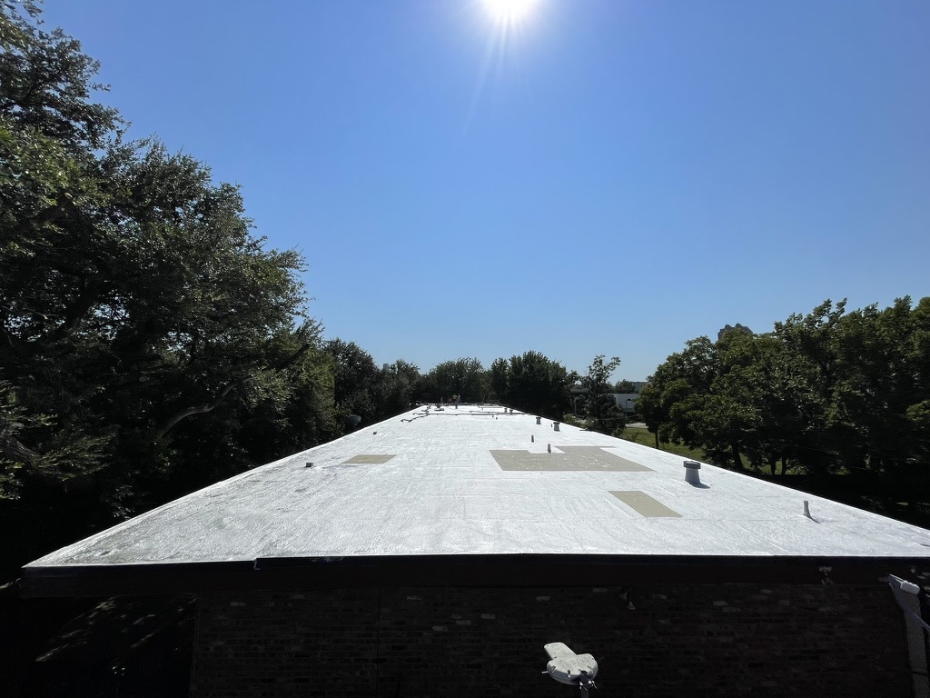 Coated section meeting the uncoated bitumen roof, showing the coverage line mid-project in Dallas