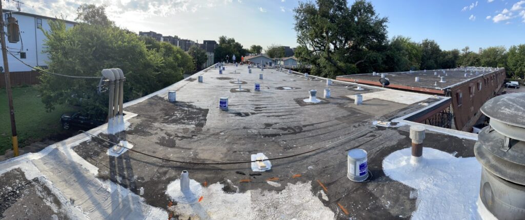 Wide view of the prepped 44,000 sq ft bitumen roof with penetrations detailed and materials staged