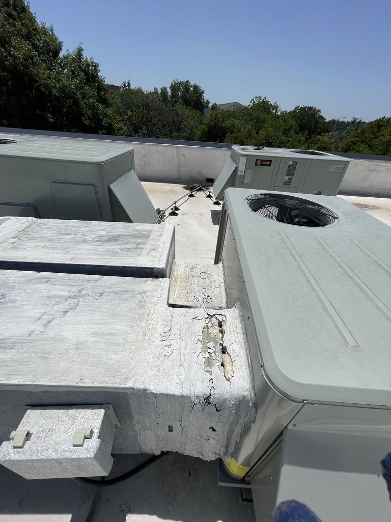 Exposed fiberglass duct wrap and cracking on a rooftop return plenum before silicone repair, Dallas Pkwy