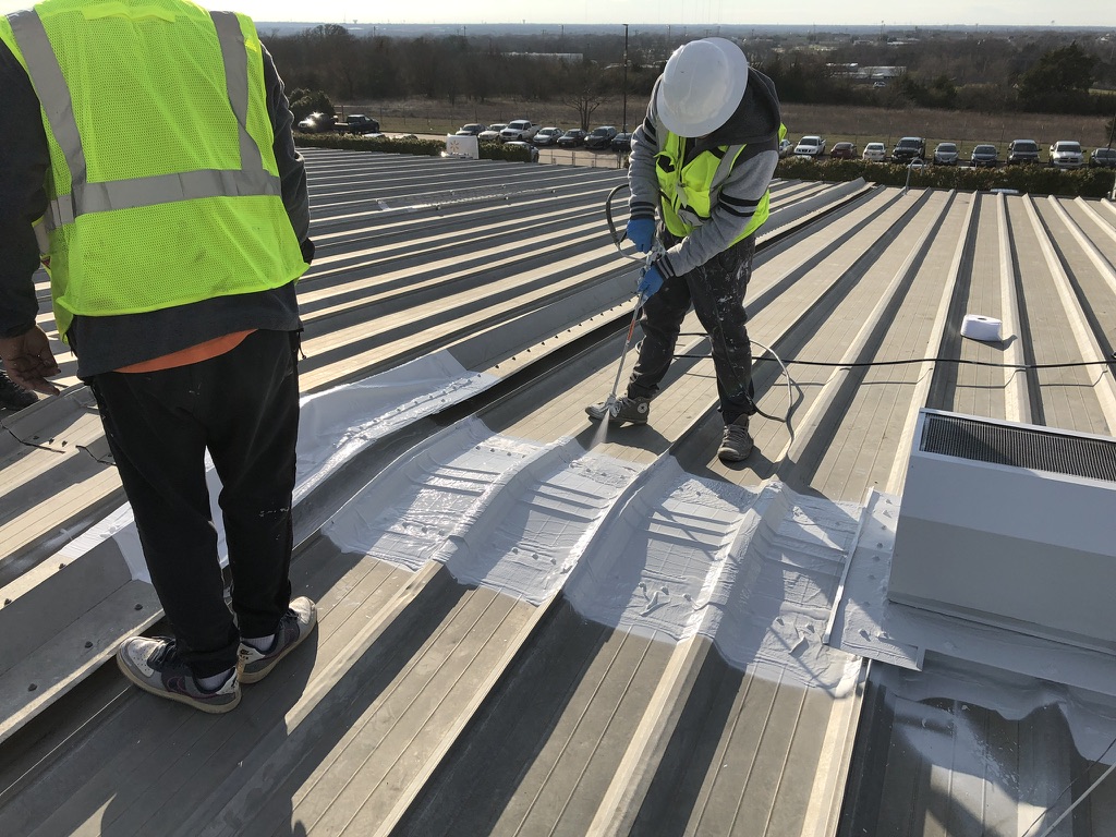 Spraying acrylic coating over reinforced seams on the galvanized metal roof in DeSoto, TX