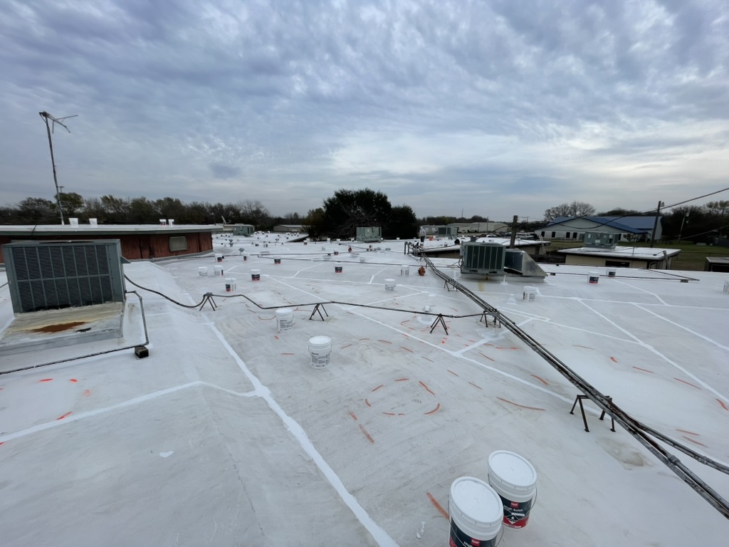 Commercial roof restoration in progress on the TPO roofing system near downtown Ennis, TX