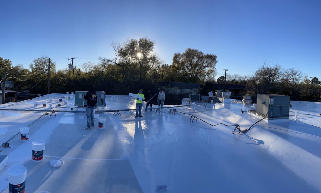 Pepper Coatings crew applying white silicone roof coating across the 27,000 sq ft commercial roof in Ennis, Texas