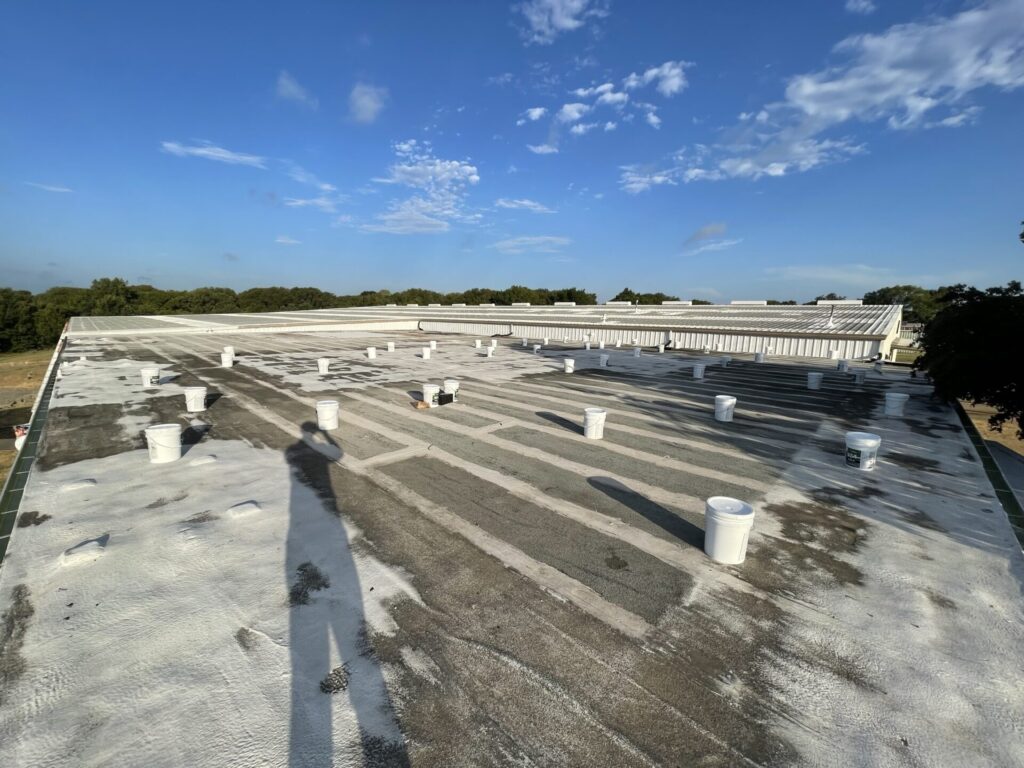 Modified Bitumen flat roof with old acrylic patch work before silicone coating at 2407 N Preston St, Ennis, TX
