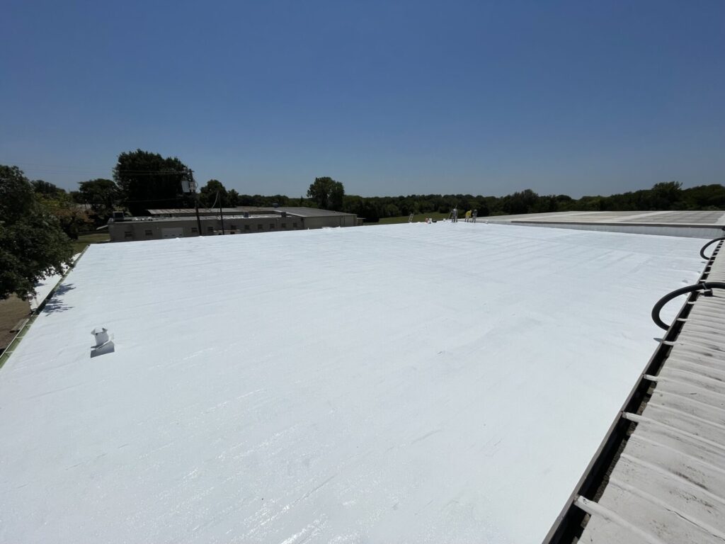 White silicone roof coating over the commercial flat roof in the northern industrial corridor of Ennis