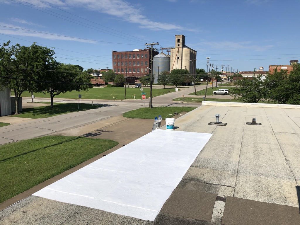 Silicone mastic applied to damaged seams and holes on the commercial flat roof near the McKinney square