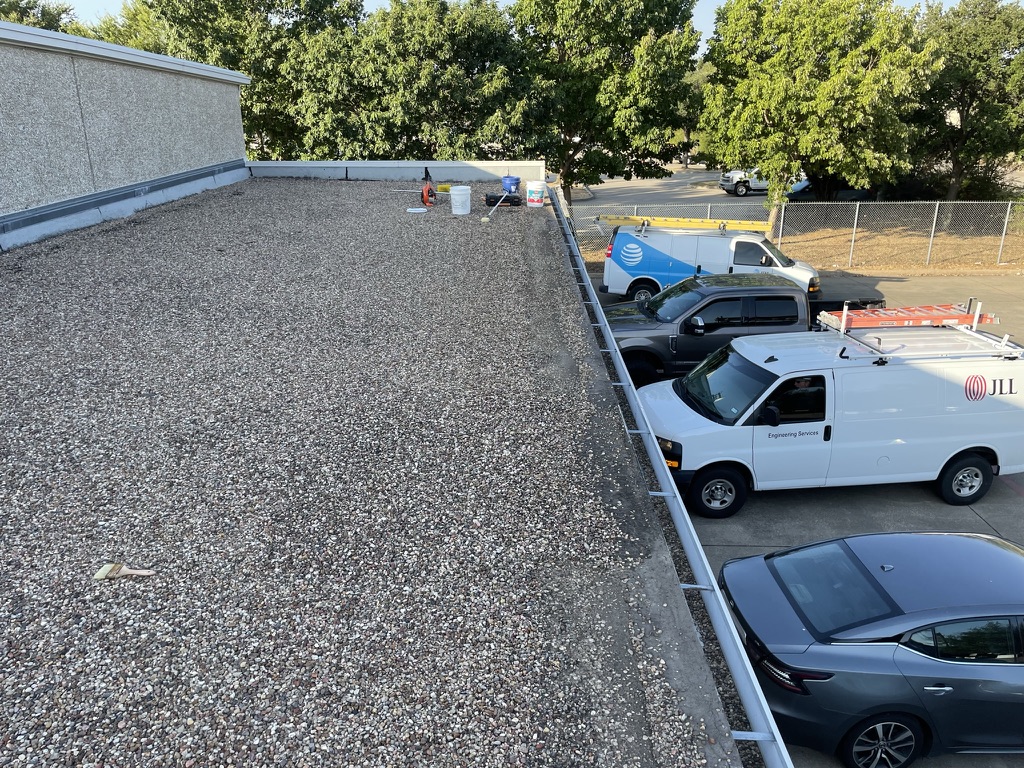 Gravel pulled back for commercial flat roof leak detection at the AT&T warehouse, 275 N Greenville Ave, Richardson, TX
