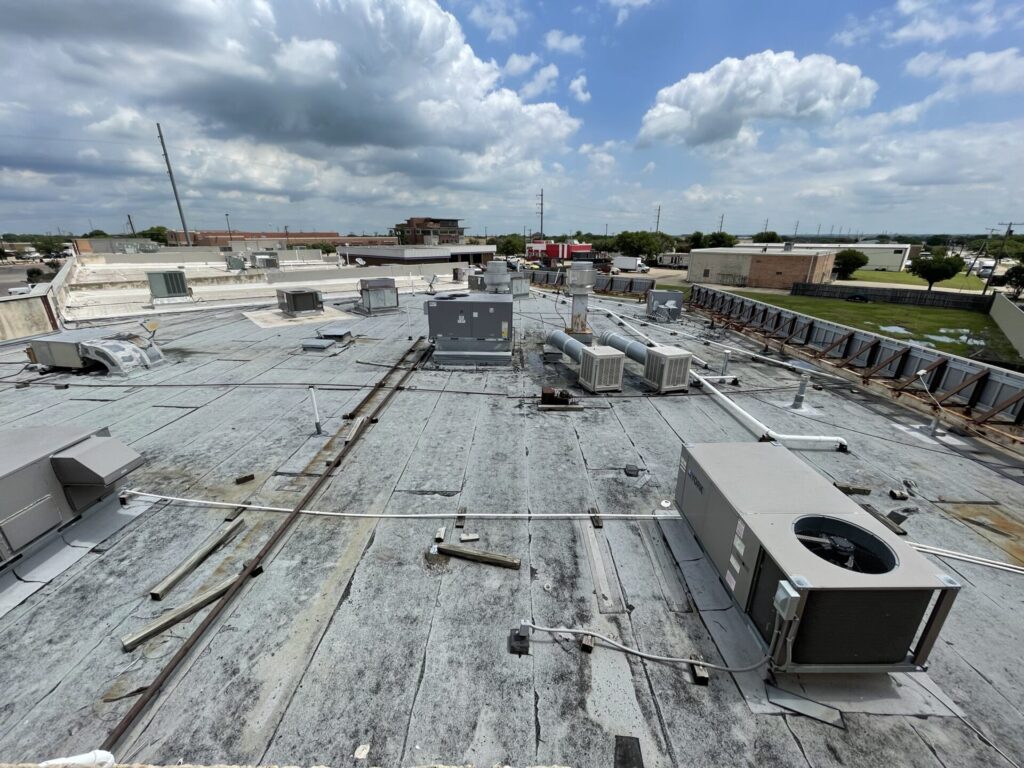 Modified Bitumen flat roof at Timberlake Shopping Center in Rowlett, TX before silicone coating — old dark surface with debris