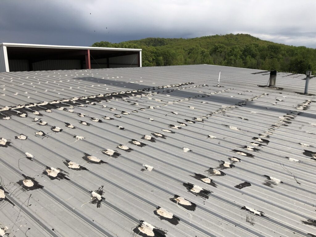Power washing the R-panel roofing system ahead of the silicone application in Russellville, AR
