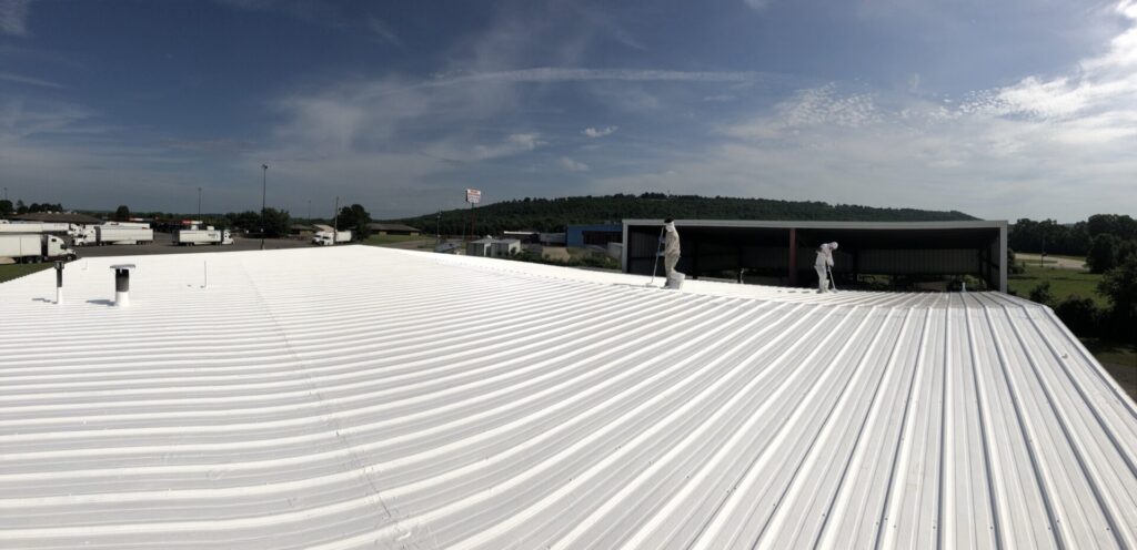 White silicone roof coating going down over the existing R-panel roof near I-40, Russellville, AR