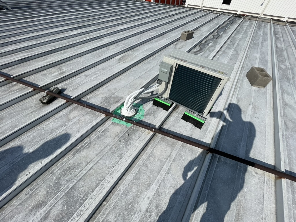 Improperly dried-in mini split roof penetration sealed with tape on a commercial metal roof in Carrollton, TX