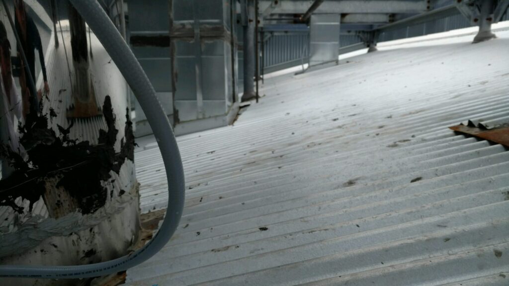 Acrylic mastic applied at open vertical seams and roof closures on the corrugated metal roof, Coppell