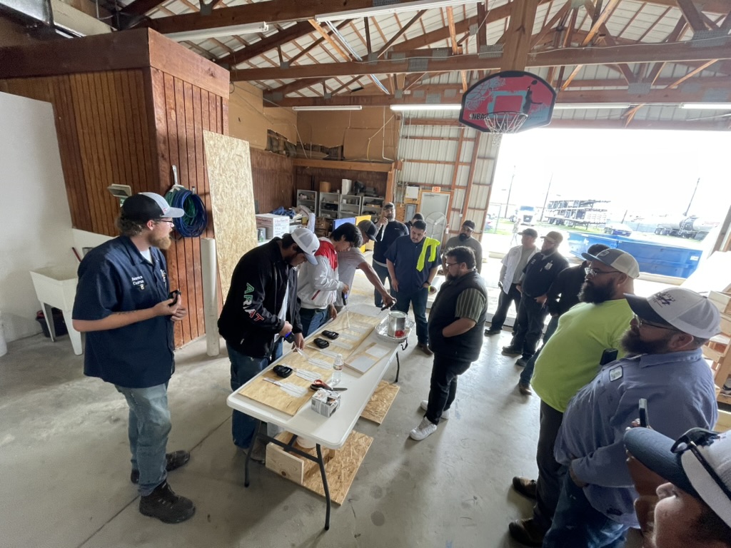 Hands-on roof coating application techniques demonstrated on sample boards during GAF training in Dallas, TX