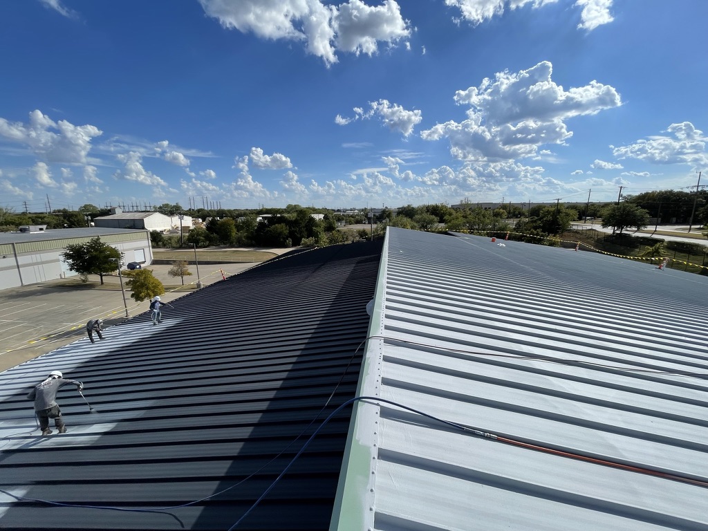 Finished charcoal coated section meeting the bare galvanized panels mid-project, Irving, Texas