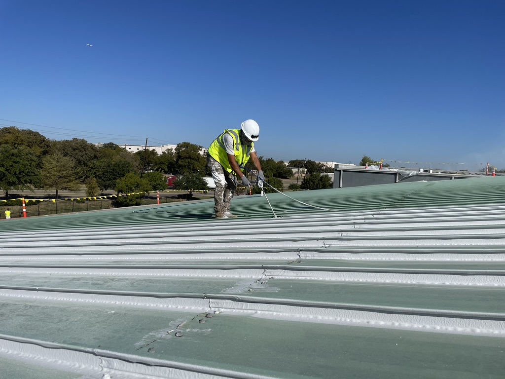 White acrylic base coat going down over the galvanized standing seam roof in Irving, TX