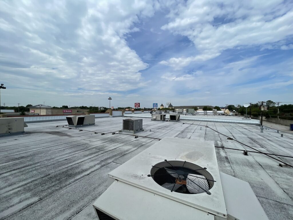 Hail impact marks visible on an oxidized mechanical RTU sidewall, Irving, TX