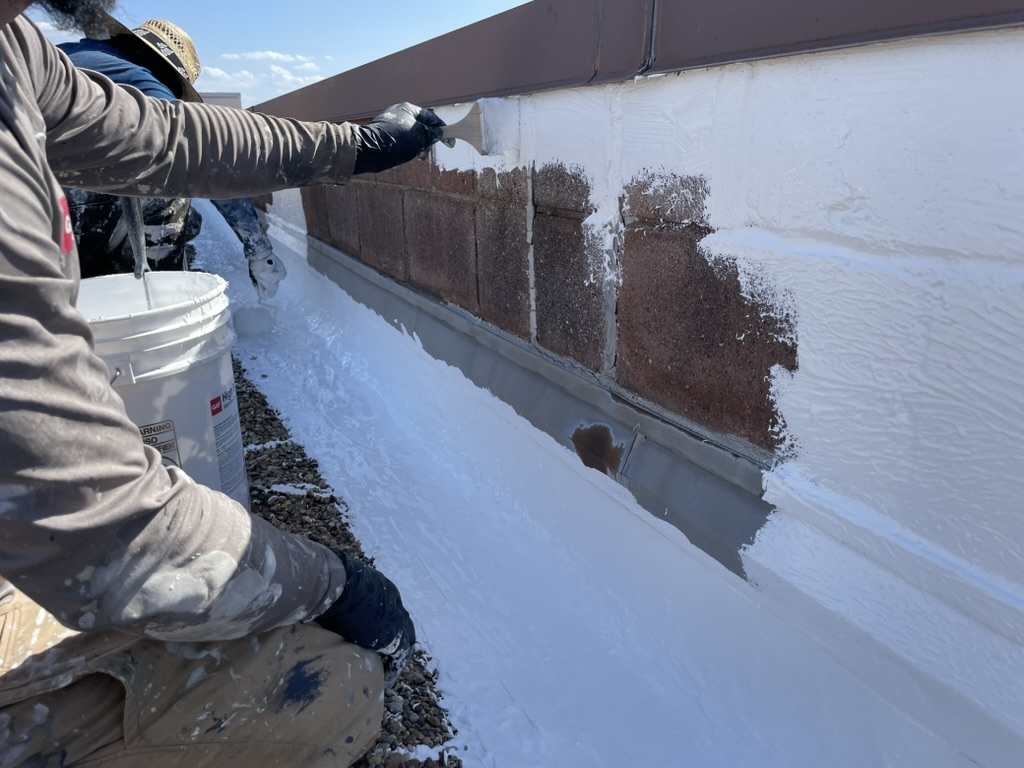 Pea gravel pulled back from the parapet wall to expose the membrane for coating, Irving, Texas