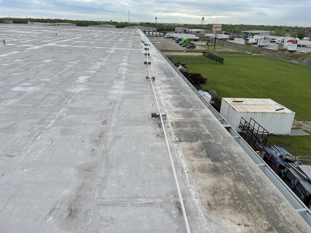 Coating failure at the roof perimeter where a 3-course fabric-reinforced termination was omitted, Saginaw