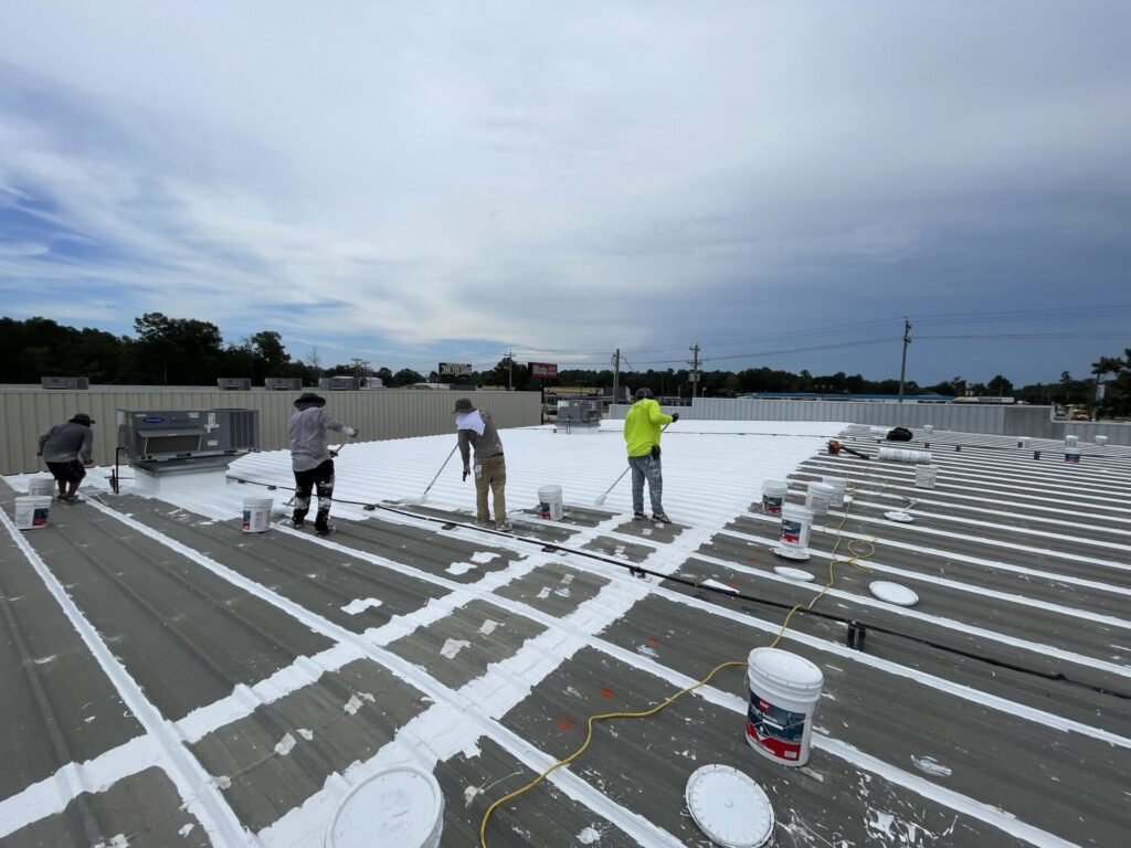 Pepper Coatings crew rolling GAF High Solids Silicone coating across the metal roof, Conroe, TX