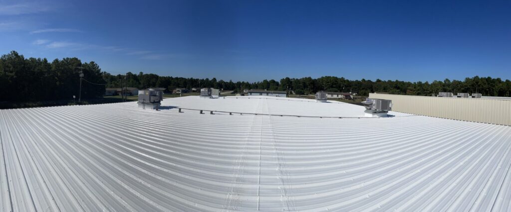 Panoramic view of the completed 9,500 sq ft white silicone roof coating at 16000 Hwy 105, Conroe, TX
