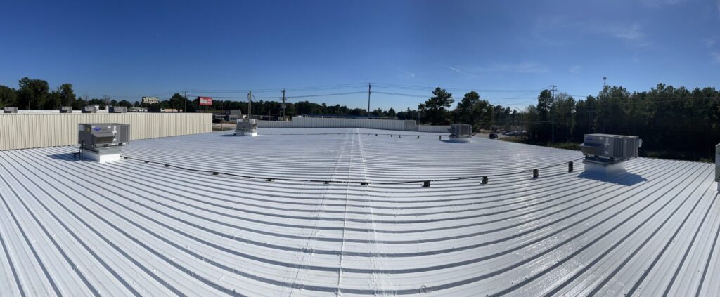 Completed white silicone roof coating with O'Reilly Auto Parts and Hwy 105 visible in the background, Conroe, TX