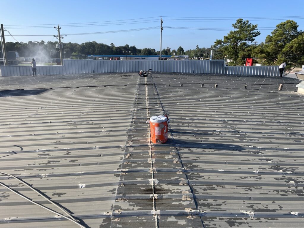 Power washing the existing metal R-panel roof before silicone coating, 16000 Hwy 105, Conroe, TX