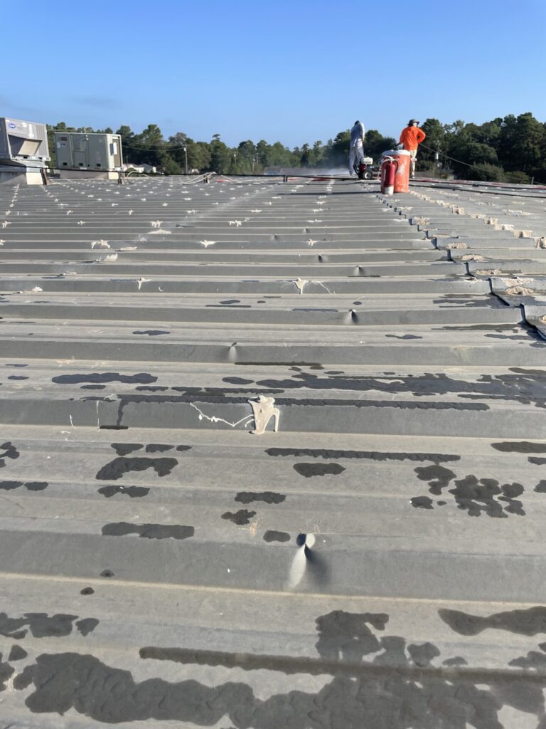 Crew power washing the existing commercial metal roof ahead of silicone application, Conroe, TX