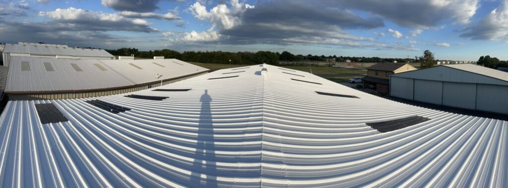 Completed white silicone coating across the R-panel roof and skylights at MWE Hangar in McKinney, Texas